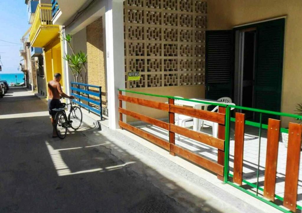 Villaggio Azzurroにある2 bedrooms appartement at Caucana finaiti casuzze finaiti Nord 40 m away from the beach with terrace and wifiの隣の自転車に腰掛けている男