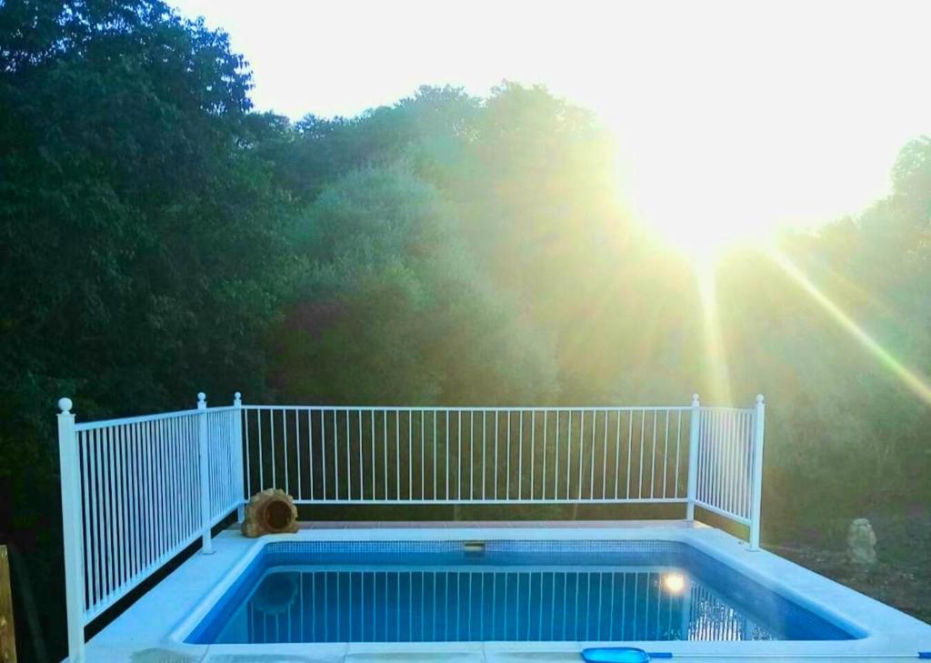 uma piscina com uma cerca branca e o sol em 2 bedrooms chalet with private pool and terrace at Cordoba em Almodóvar del Río