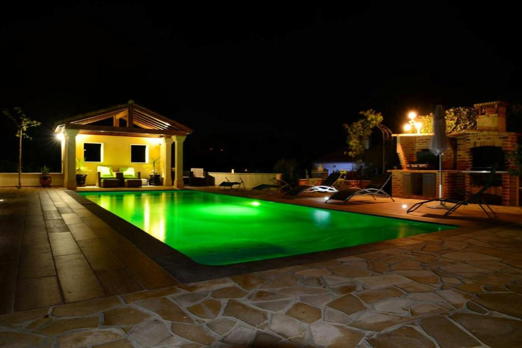 - une piscine avec éclairage vert la nuit dans l'établissement Villa de 6 chambres avec piscine partagee et wifi a Sainte Valiere, à Sainte-Vallière