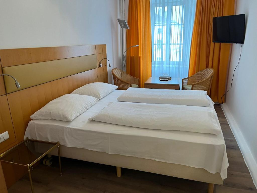 a hotel room with two beds and a television at City Hotel Post 22 in Braunau am Inn