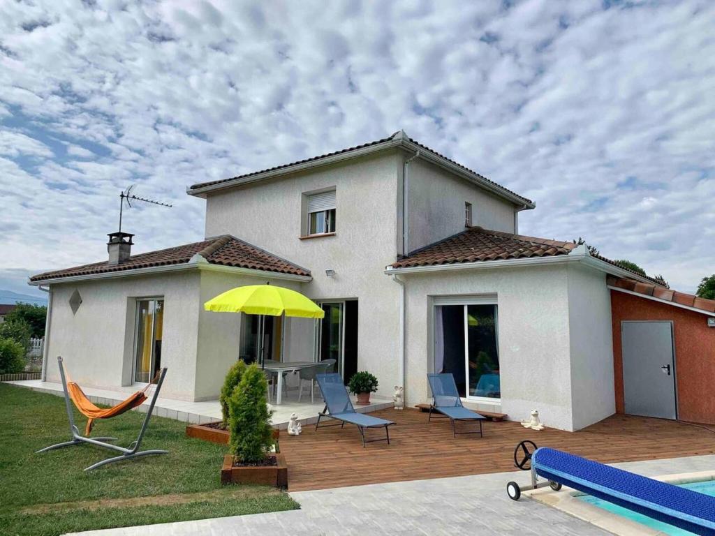 ein Haus mit einer Terrasse mit Stühlen und einem Sonnenschirm in der Unterkunft Villa de 2 chambres avec piscine privee terrasse et wifi a Saint Gaudens in Saint-Gaudens