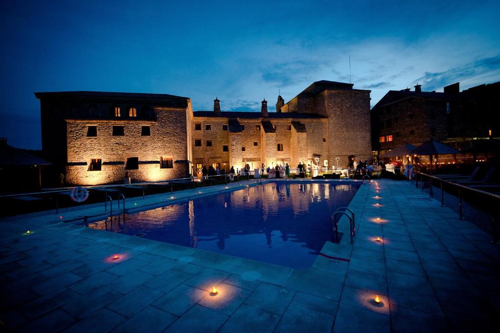 una gran piscina frente a un castillo por la noche en Hotel & SPA Monasterio de Boltaña, en Boltaña