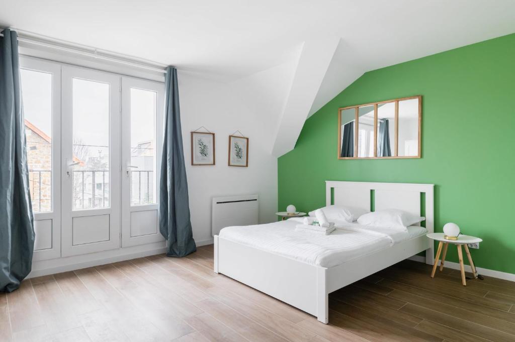 ein Schlafzimmer mit einem weißen Bett und einer grünen Wand in der Unterkunft Studio 20m2 Lumineux avec balcon - 2P in La Courneuve
