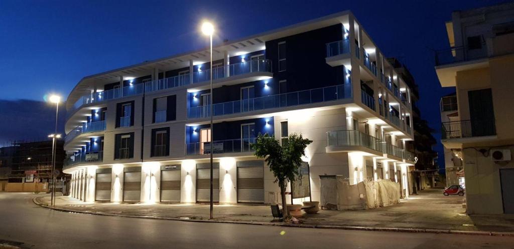 um grande edifício branco com luzes acesas à noite em La Vela Apulia Seaside Residence em Margherita di Savoia