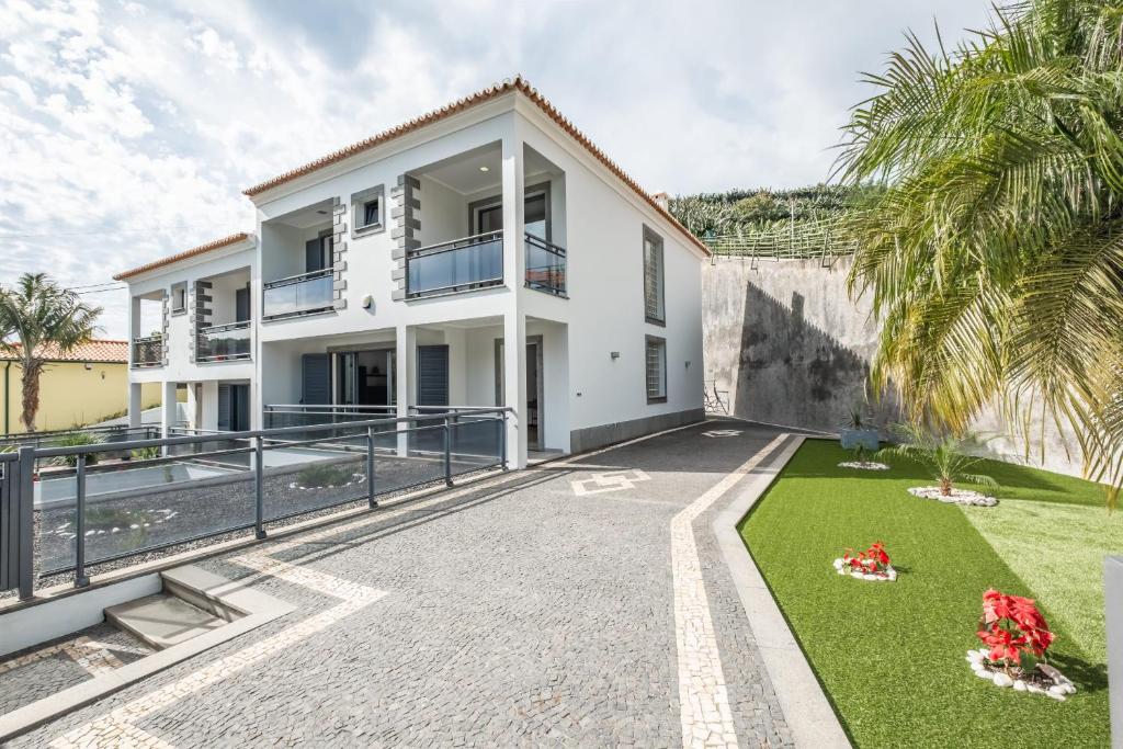 ein weißes Haus mit einem Innenhof und Palmen in der Unterkunft Til Home by Madeira Sun Travel in Funchal
