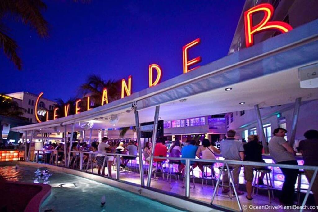 a group of people sitting at a bar at night at BEST DEAL! 2 Bedroom Modern Beachfront by YouRent! in Miami Beach