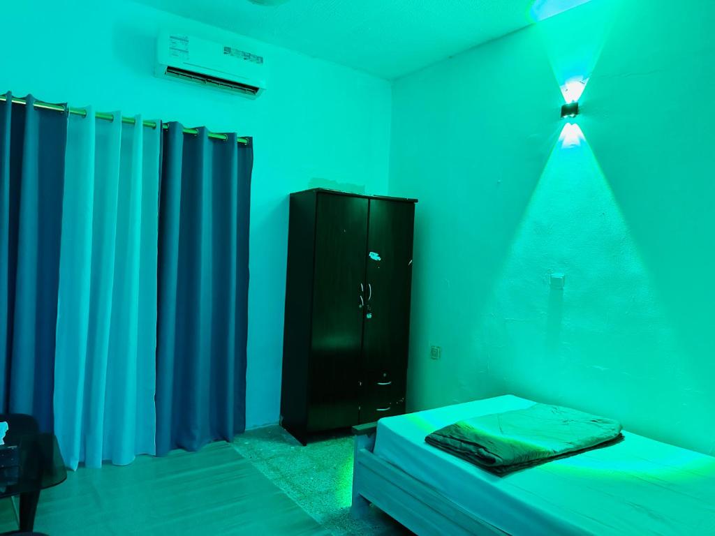 a room with a bed and a cabinet with blue lights at Room for rent in Sharjah