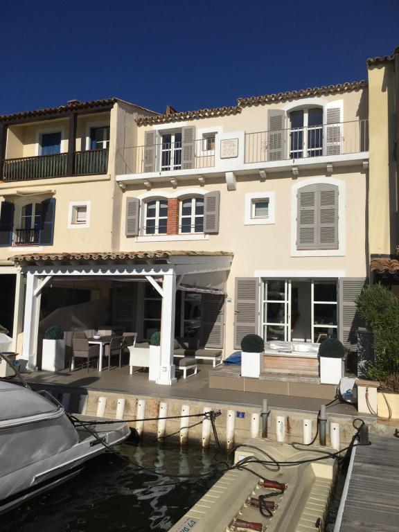 un grand bâtiment blanc avec un bateau dans l'eau dans l'établissement VILLA DE LUXE A PORT GRIMAUD, à Grimaud