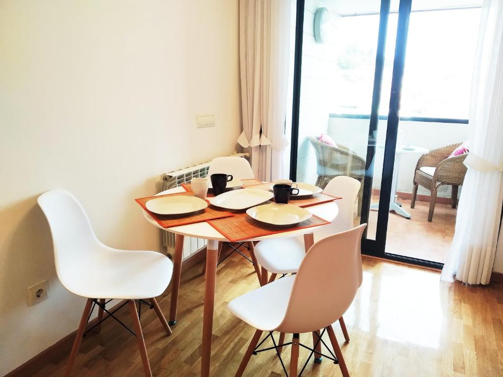 a dining room table with white chairs around it at HIKARI, centro Luanco con PARKING in Luanco