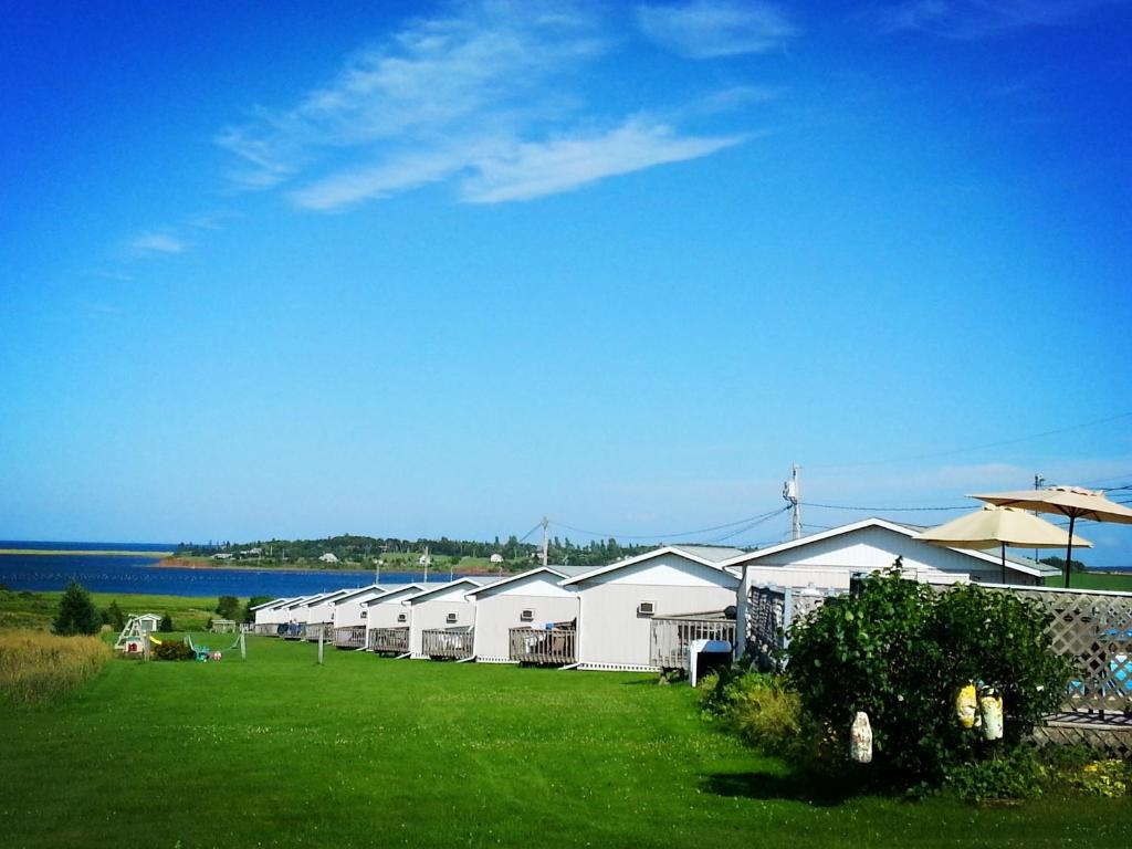 a row of white buildings on a grass field at Blue Crest Cottages in North Rustico