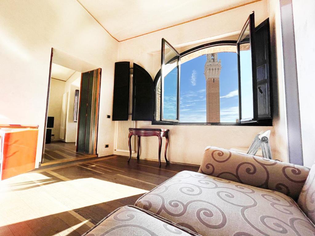een kamer met een bank en een raam met een klokkentoren bij Il Campo 8: Piazza del Campo in Siena