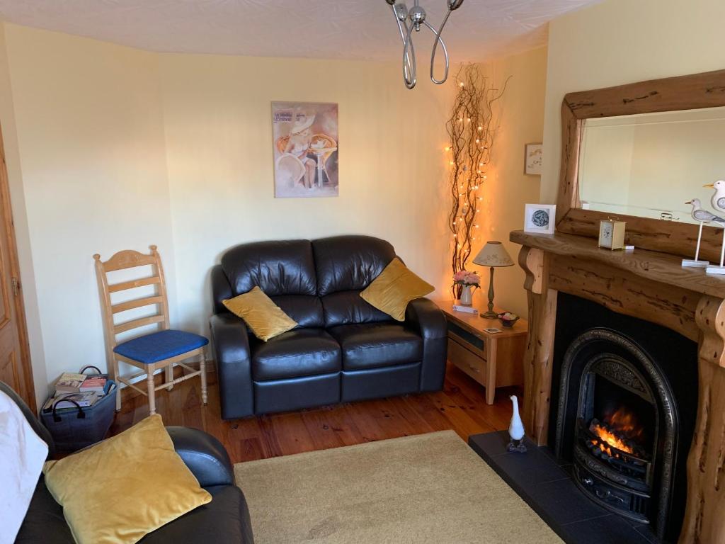 a living room with a leather couch and a fireplace at Bush Lodge Bushmills in Bushmills