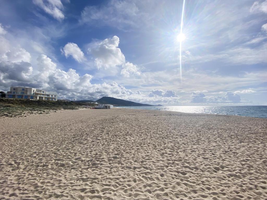 a sandy beach with the sun in the sky at L'Attico Blu - Affitti Brevi Italia in Valledoria