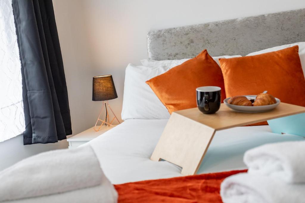 ベルファストにあるCastlereagh guest Houseのベッド(オレンジ色の枕付)、テーブルの上に食べ物を置いて