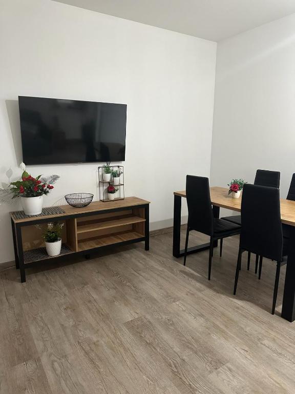 ein Wohnzimmer mit einem TV, einem Tisch und Stühlen in der Unterkunft APARTAMENT Z TARASEM STELLA in Sanok