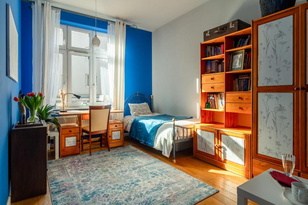 1 dormitorio con paredes azules, 1 cama y escritorio en Botaniczny Pokój, en Cracovia