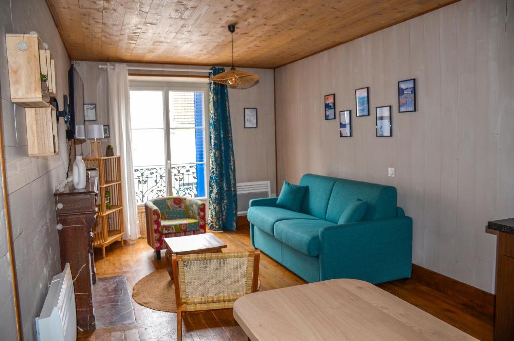 a living room with a blue couch and a table at Gite "La belle échappée" à 5 minutes du lac in Clairvaux-les-Lacs