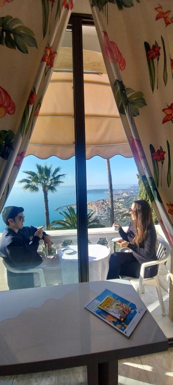 zwei Personen sitzen an einem Tisch mit Meerblick in der Unterkunft Olguita in Menton