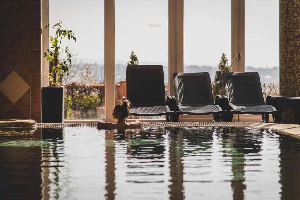 una mujer sentada en el agua en una piscina en Főnix Wellness *** 1 A épület, en Hévíz