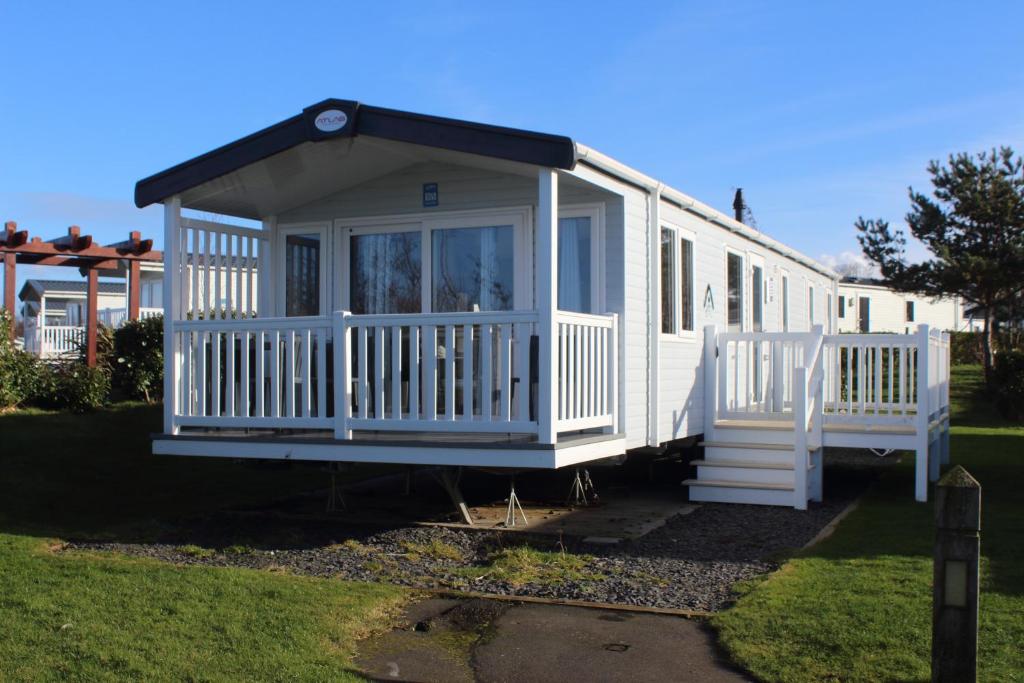 a white tiny house with a porch at Cjs family caravans in Ayr