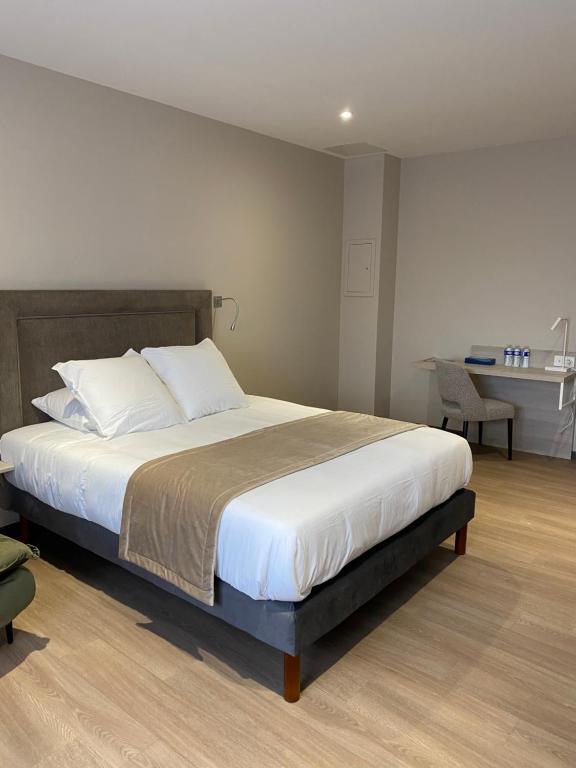 a bedroom with a large bed and a desk at Hôtel du Commerce-restaurant au Couteau in Nogent