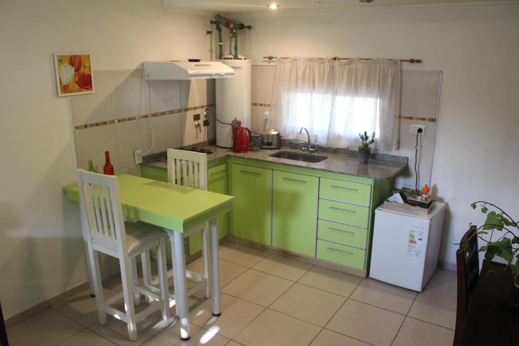 a kitchen with green cabinets and a table and a sink at Departamento Encantador monoambiente Domaine Laborde I in Mendoza