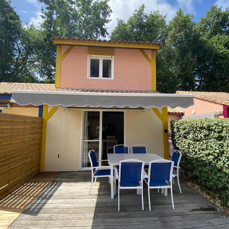 une table et des chaises sur une terrasse avec une maison dans l'établissement Villa Soustons Plage / Résidence les villas du lac avec piscine, à Soustons