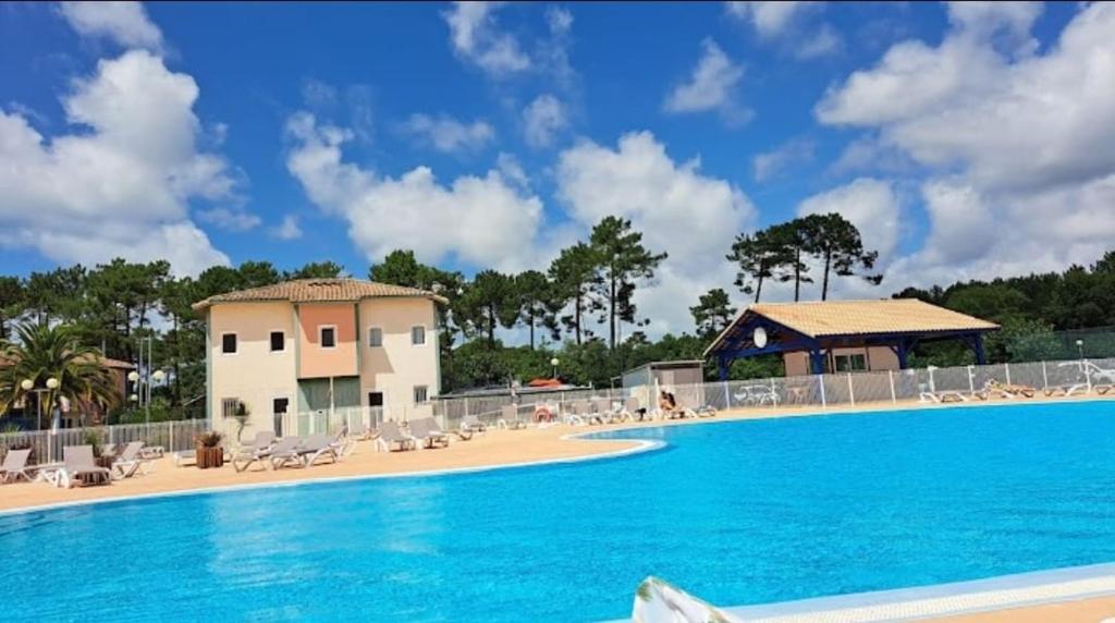 een groot zwembad met stoelen en een gebouw bij Villa Soustons Plage / Résidence les villas du lac avec piscine in Soustons