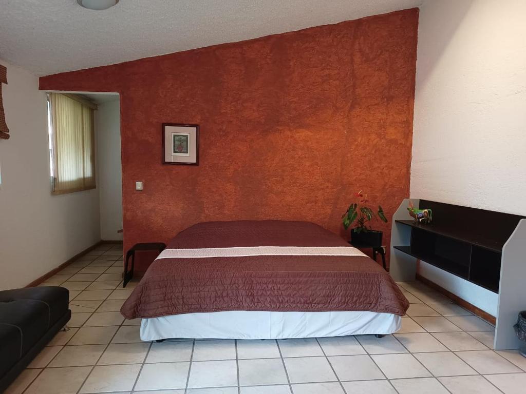 um quarto com uma cama com uma parede vermelha em COLIVING em Cuernavaca