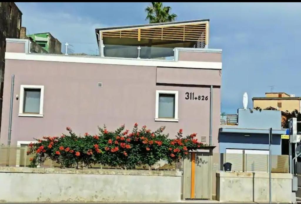 a pink building with flowers on the side of it at B&B CaselloA Suites in Siracusa