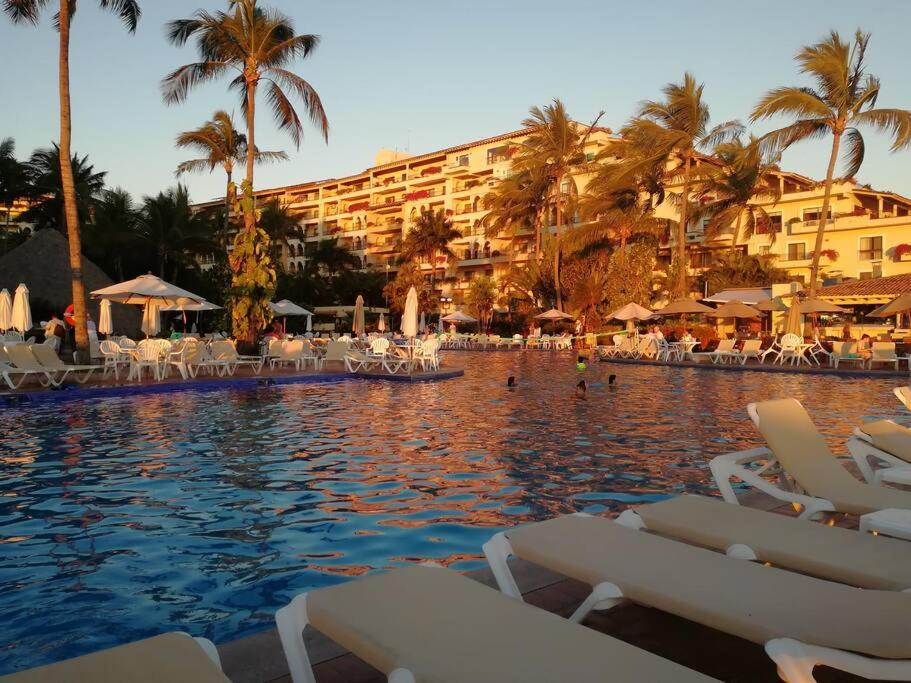 a large swimming pool with chairs and a hotel at Espectacular Villa Frente al Mar in Puerto Vallarta