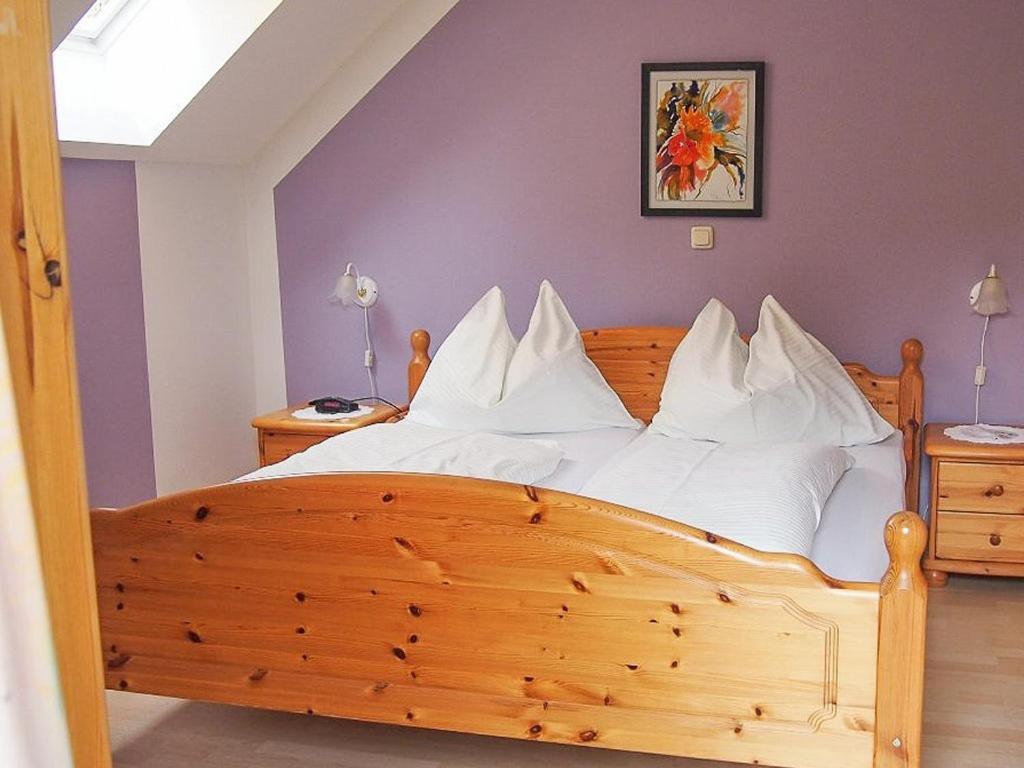 a bedroom with a wooden bed with white pillows at Pension Kreuzberghof in Großklein