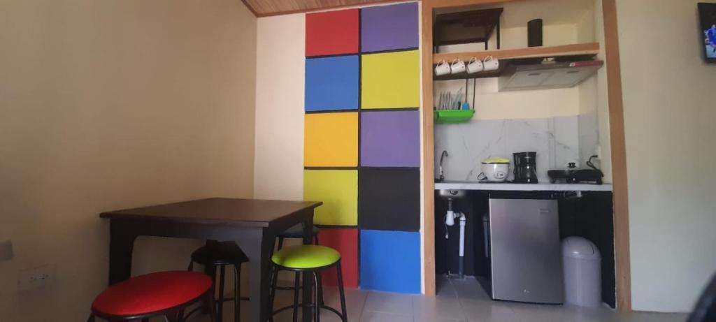 a colorful wall in a kitchen with a table and stools at Cabinas Rubik 1 in Savegre