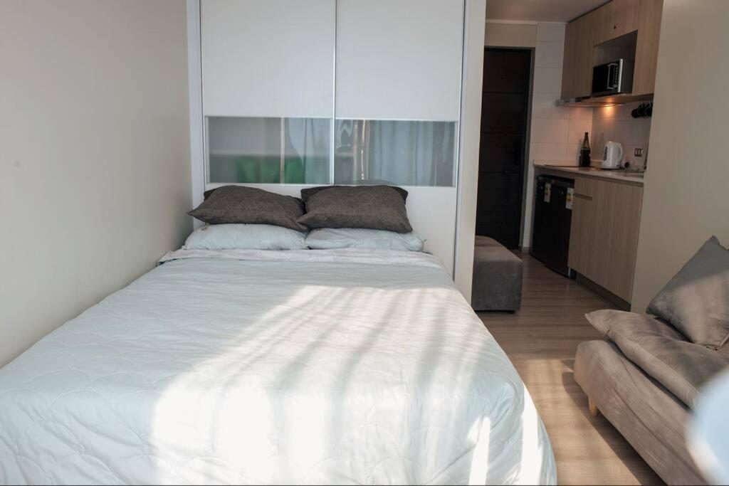 比尼亞德爾馬的住宿－Estudio cómodo y full equipado en Viña，一张白色的床,位于一个配有沙发的房间