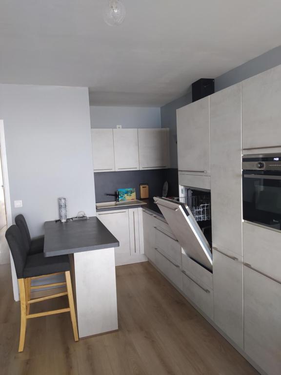 une cuisine avec des armoires blanches et un comptoir noir dans l'établissement L'Albatros, à Courseulles-sur-Mer