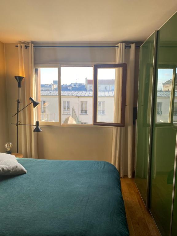 a bedroom with a blue bed and a window at Apartment in Montmartre in Paris