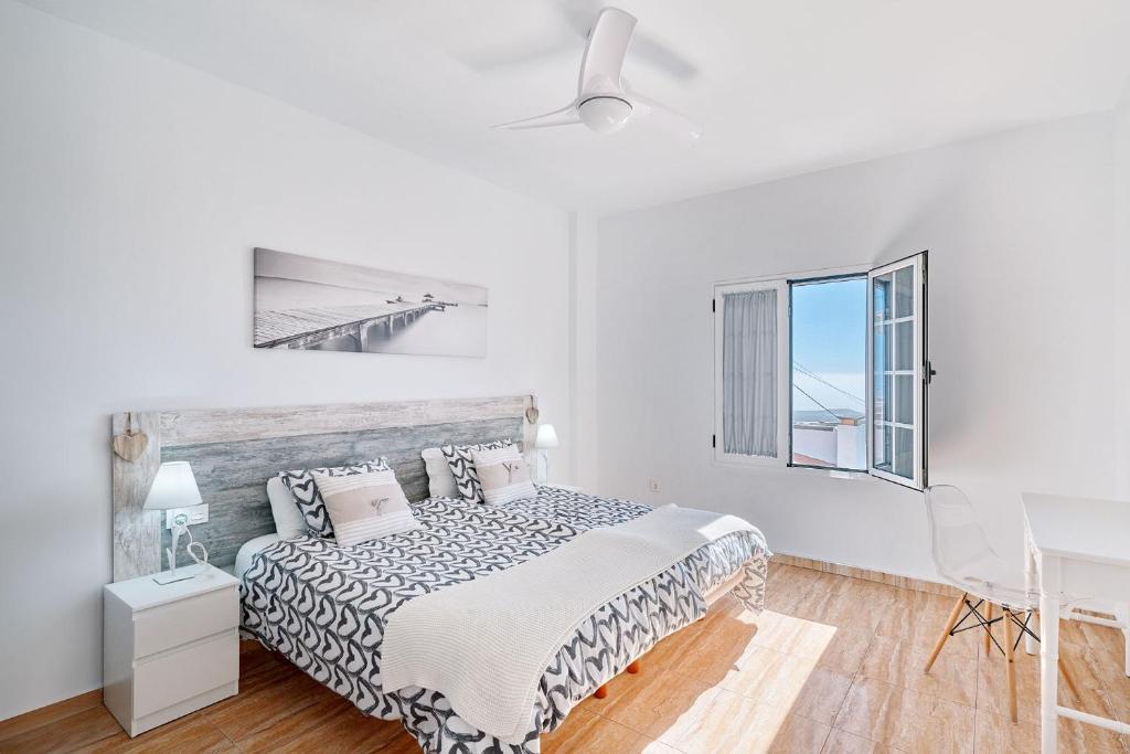 Un dormitorio blanco con una cama y una ventana. en Casa Fernando, en Granadilla de Abona