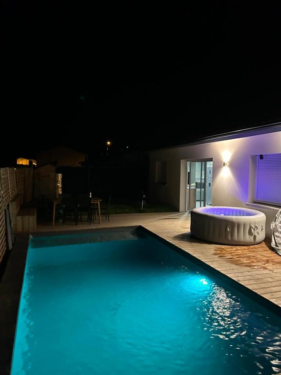 una piscina por la noche con un spa en Aux portes de bordeaux Maison cocooning avec Piscine spa chauffé, en Ambarès-et-Lagrave