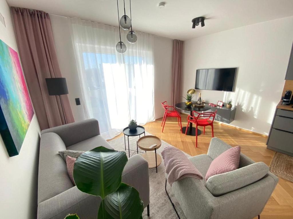 sala de estar con sofá, sillas y TV en Stylische Wohnung mit Balkon, en Graz