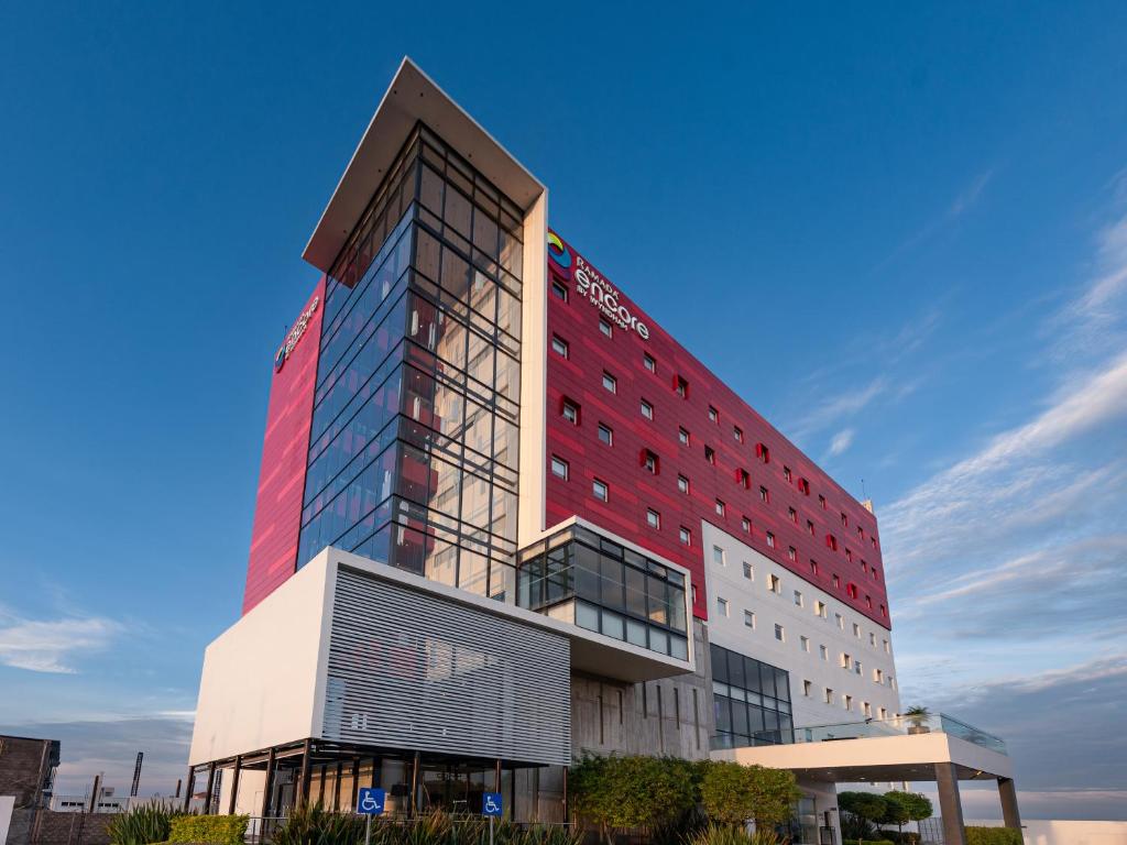 a tall red and white building with a blue sky at Ramada Encore by Wyndham Aguascalientes in Aguascalientes