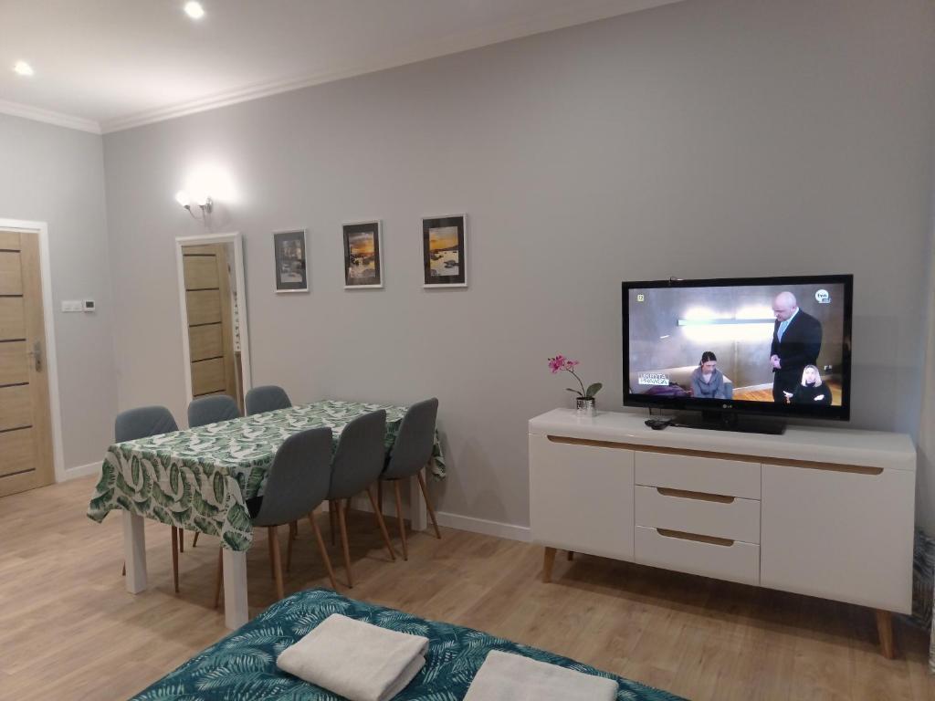 a living room with a table and a flat screen tv at Apartament na Przedmieściu in Wrocław