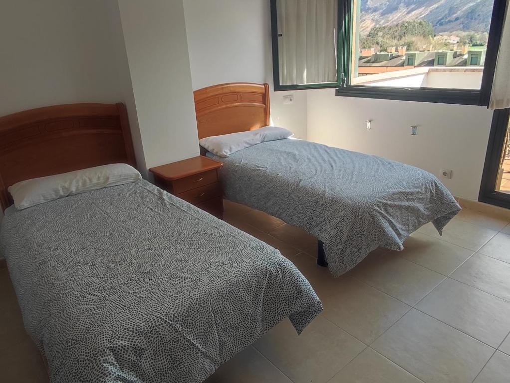 Duas camas num quarto com uma janela em Precioso apartamento con vistas em Posada de Llanes