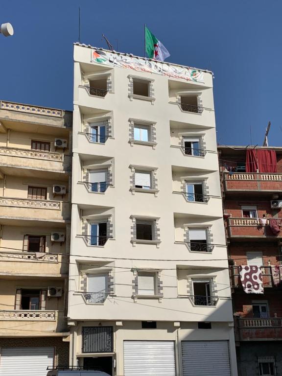een hoog wit gebouw met ramen en een vlag erop bij عمارة فلسطين 