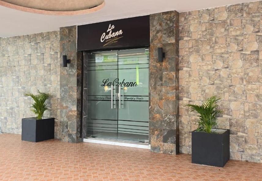 a store front with two potted plants in front of it at La Cubana Hotel & Suites in Colón