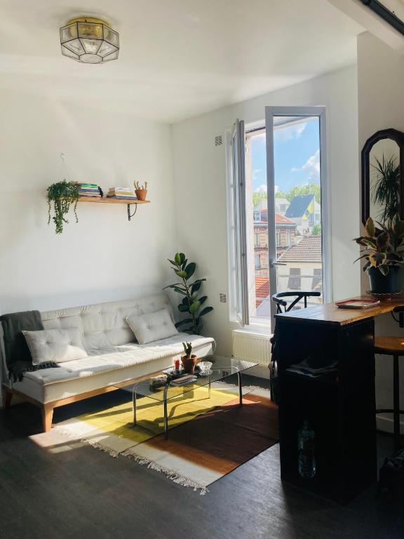 un salon avec un canapé et une grande fenêtre dans l'établissement APPARTEMENT AU COEUR DES JEUX OLYMPIQUES., à LʼÎle-Saint-Denis
