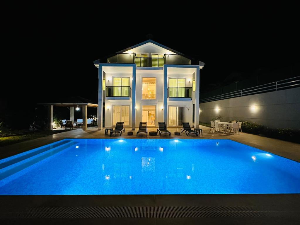 a large swimming pool in front of a house at night at Sunshine Villa in Fethiye