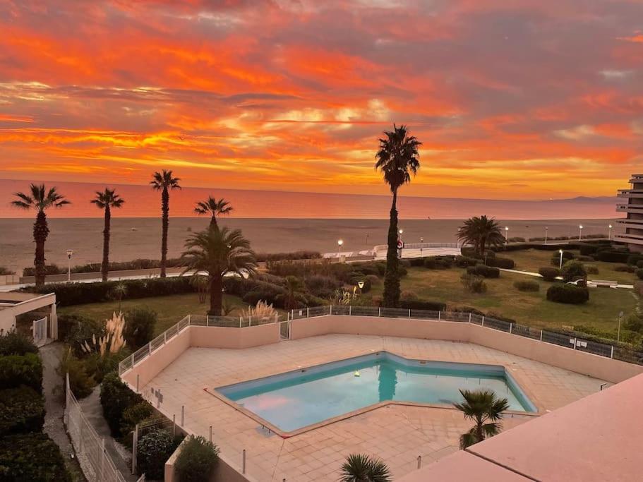 - une piscine avec vue sur la plage au coucher du soleil dans l'établissement Bel appartement vue mer accès direct plage, à Canet