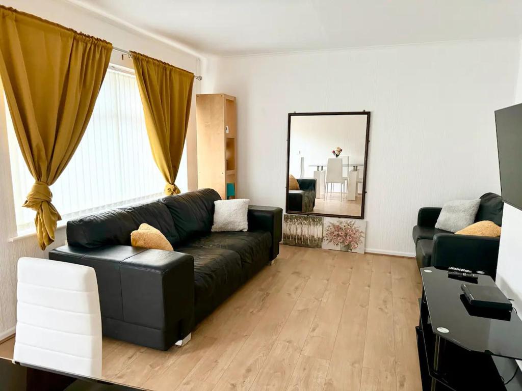 a living room with a black couch and a mirror at Cosy & Quiet House close to Etihad and City Centre in Manchester