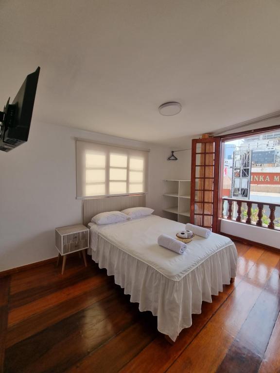 um quarto com uma cama com lençóis brancos e uma janela em Hostel Prada em Lima