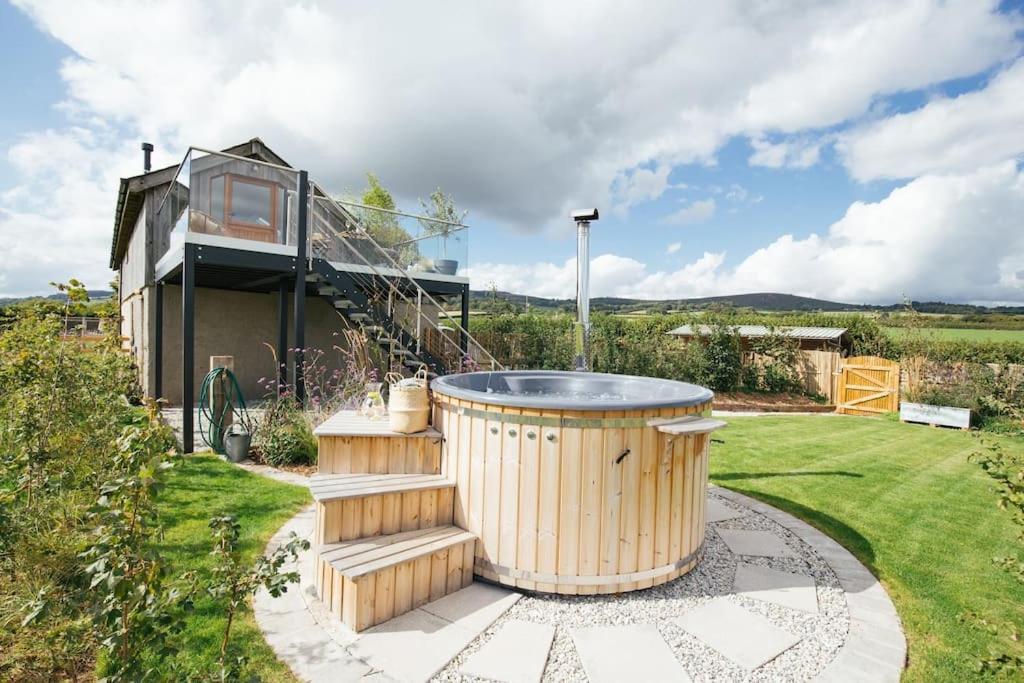 a hot tub in the yard of a house at Luxury Devon Hayloft with panoramic Dartmoor views in Ilsington